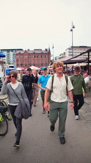A group of people walking on a pedestrian path in an urban area with buildings and street lamps in the background. 1