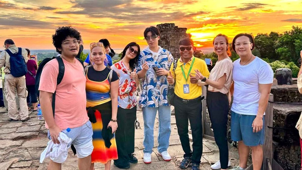 A group of people standing on a stone platform with a sunset in the background. 5