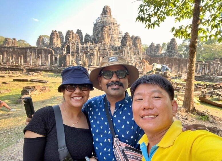 Three people taking a selfie with Angkor Wat temple in the background. 4