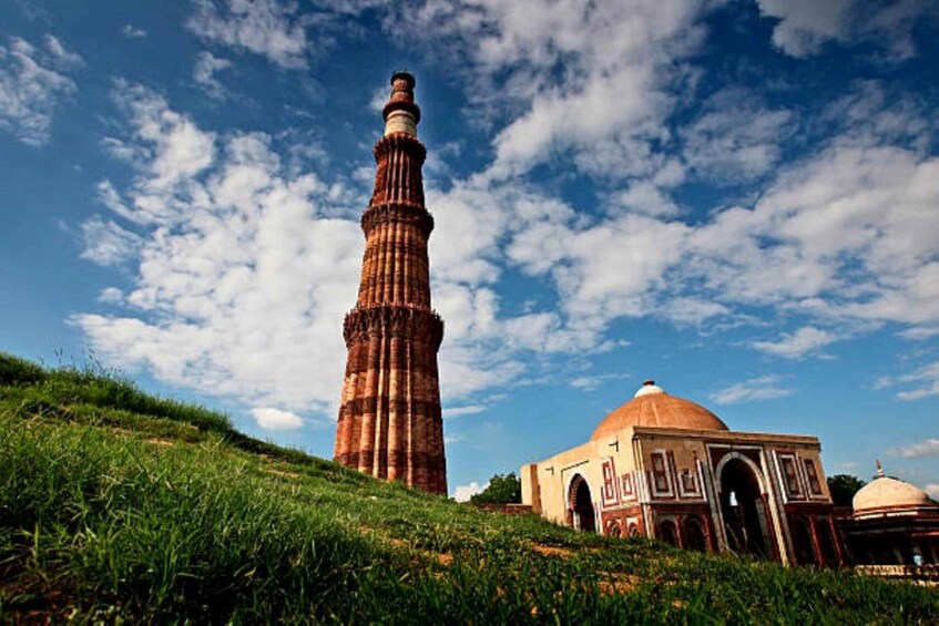 A tall minaret and a mosque with domes under a blue sky with clouds. 3