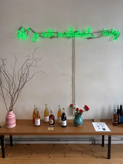 A table with bottles and a neon sign. 3