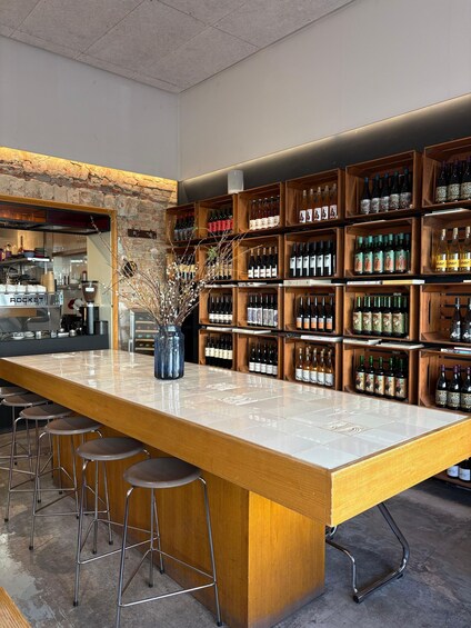 A bar with a long counter, wooden shelves with bottles, and bar stools. 5