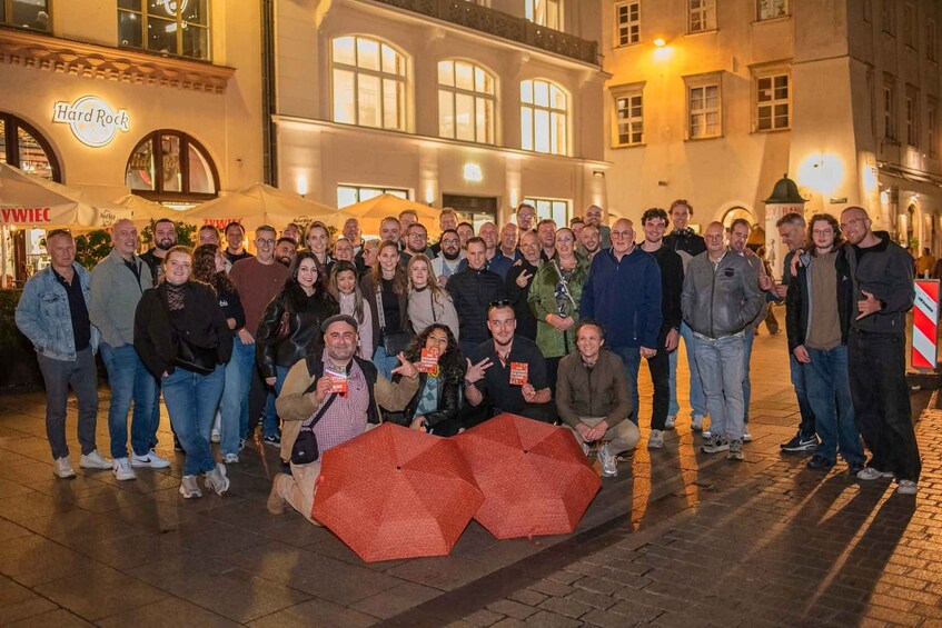 Un groupe de personnes posant pour une photo dans un environnement urbain, avec des bâtiments et un restaurant Hard Rock en arrière-plan. 1