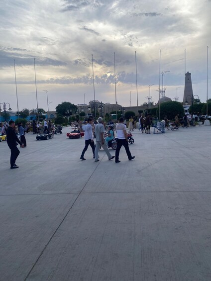 A busy public square with people walking, a horse, and a market stall. 2