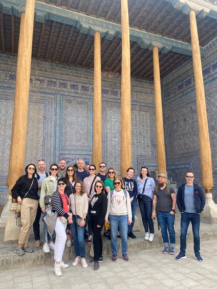 A group of people standing in front of a building with intricate tile work and large wooden columns. 4