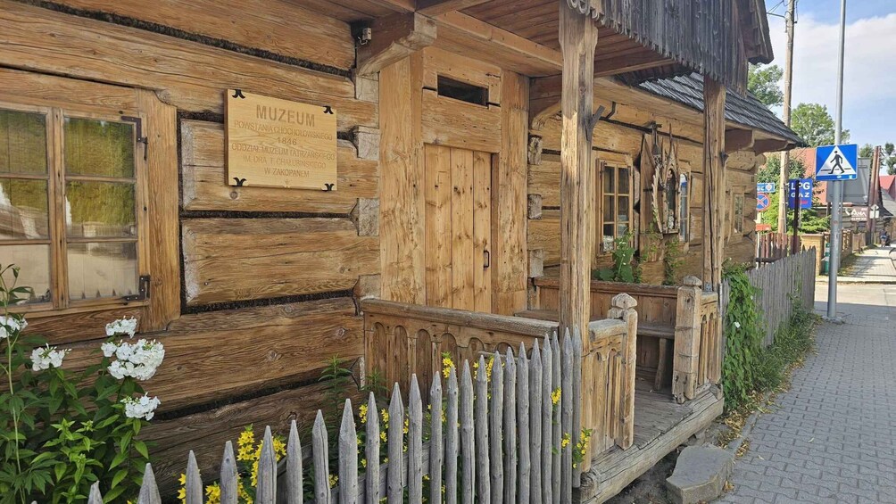 A wooden building with a signboard, a wooden fence, and flowers. 4