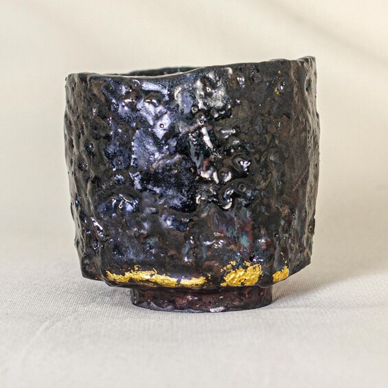 A textured ceramic mug with a rough exterior and a golden rim. 5