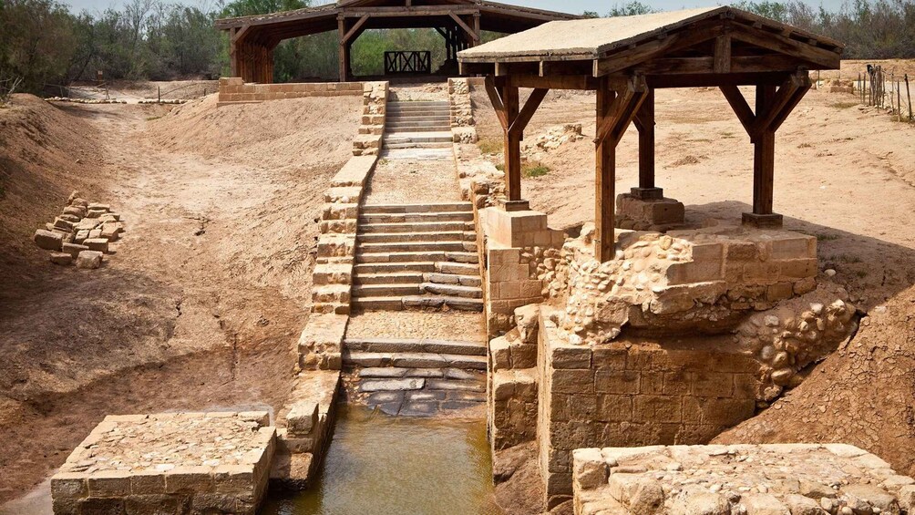 An ancient aqueduct with stone steps leading to a water channel. 1