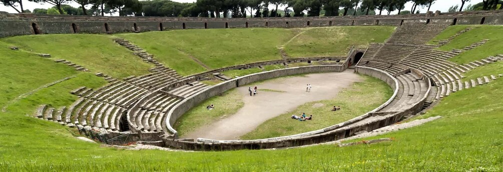 An ancient amphitheater with stone seating and a central stage area. 2
