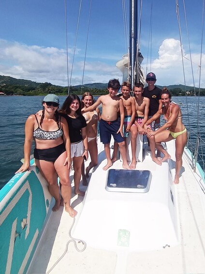 A group of people on a sailboat with a clear sky and calm water. 4