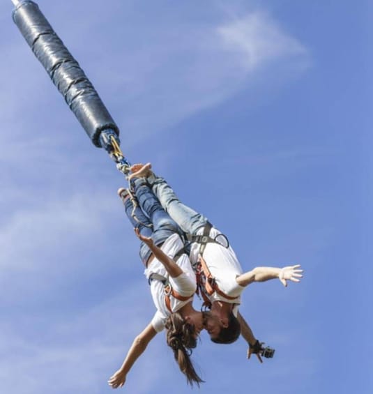 Two people bungee jumping with a clear blue sky in the background. 1