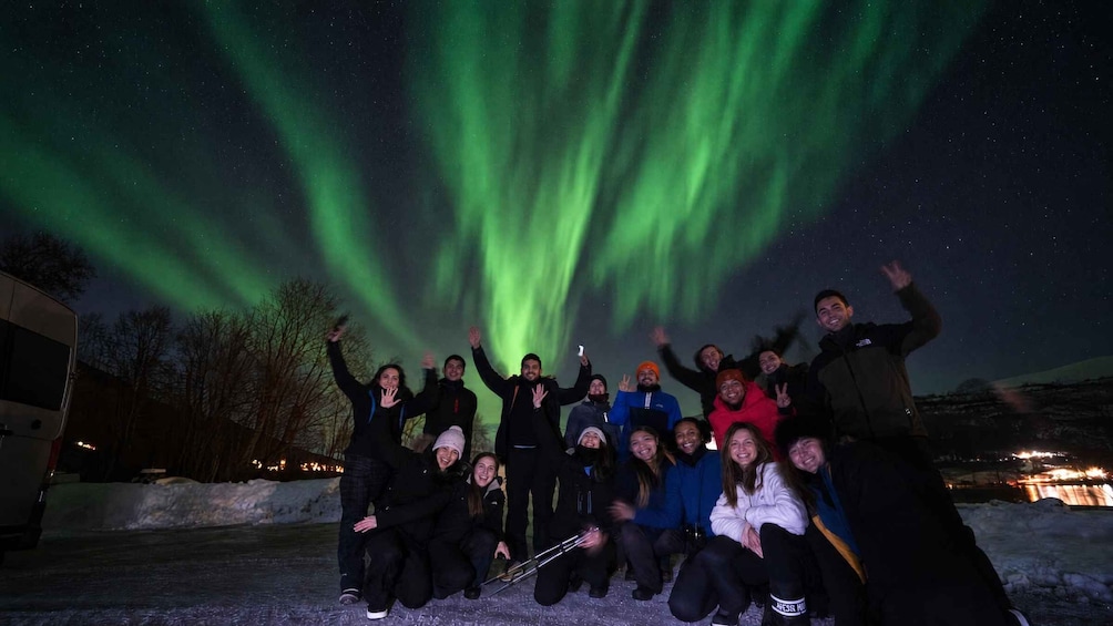 A group of people posing under the Northern Lights. 1