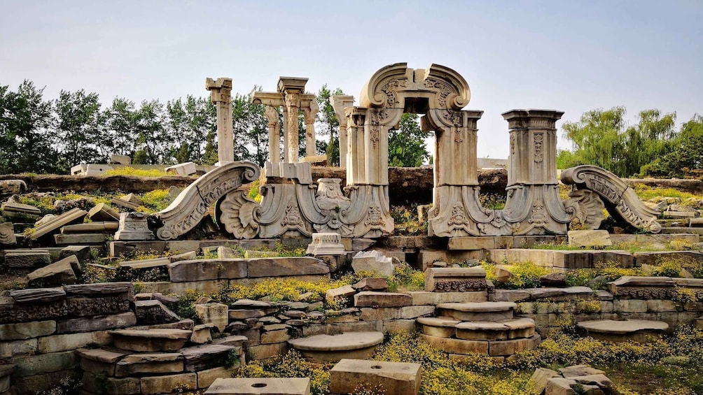 Ancient ruins with columns and decorative elements, surrounded by vegetation. 2