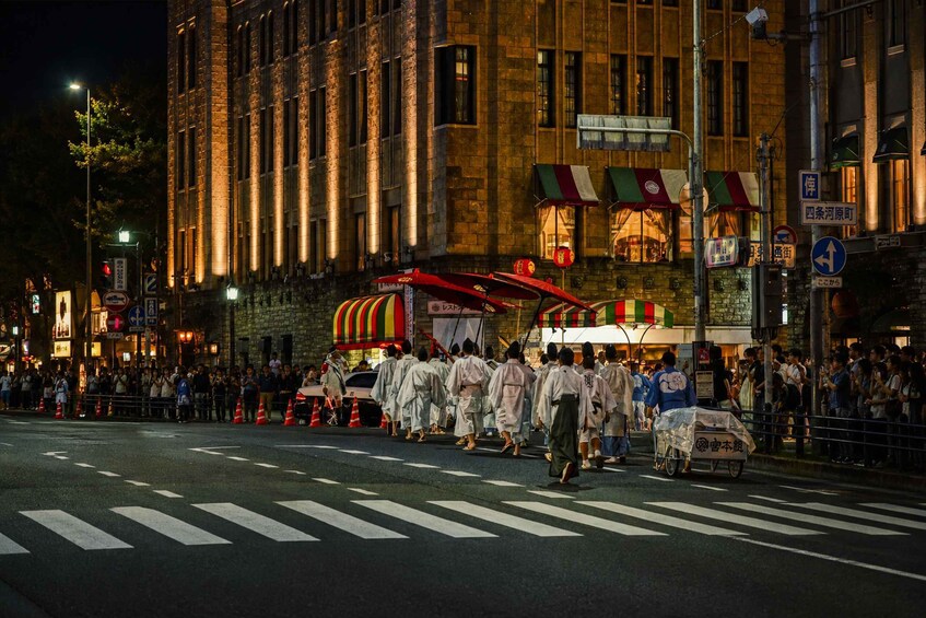 A nighttime street scene with a crowd of people in traditional attire, a street vendor cart, and illuminated buildings. 3