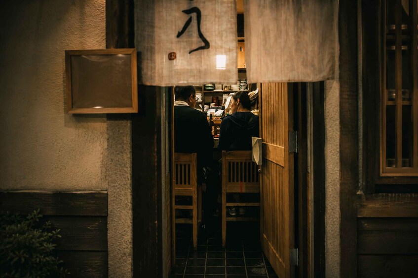 A narrow alleyway with wooden doors and a hanging sign with Japanese characters. 2