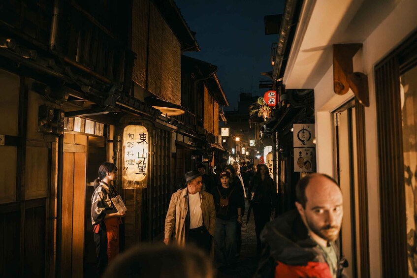 A narrow street at night with traditional buildings and illuminated signs. 4