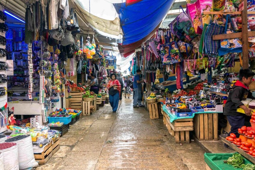 A bustling indoor market with various stalls selling fruits, vegetables, and colorful bags. 5
