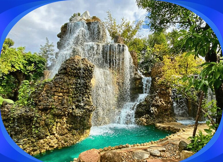 A waterfall cascading over rocks into a turquoise pool surrounded by lush greenery. 5