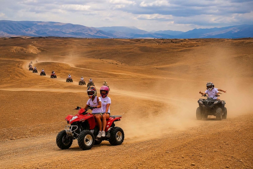 A group of people riding ATVs on a dusty desert road with mountains in the background. 5
