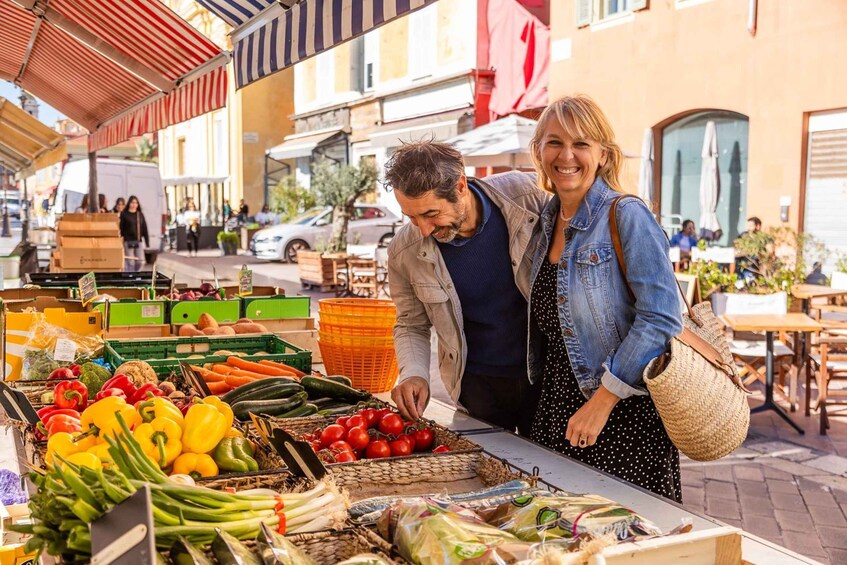 A street market with fresh produce and a couple browsing. 1