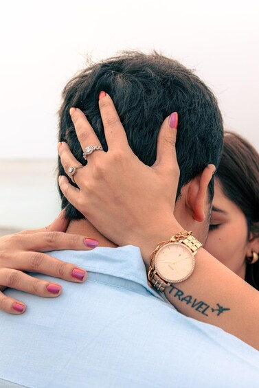 A person with a tattoo of 'TRAVEL' and an airplane on their arm, wearing a watch and a ring. 2