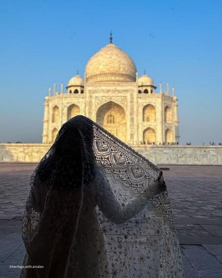 A close-up of a patterned fabric with a Mughal architectural structure in the background. 2