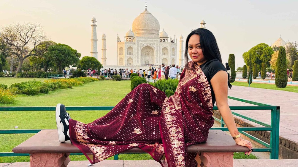 A person sitting on a bench with the Taj Mahal in the background. 3