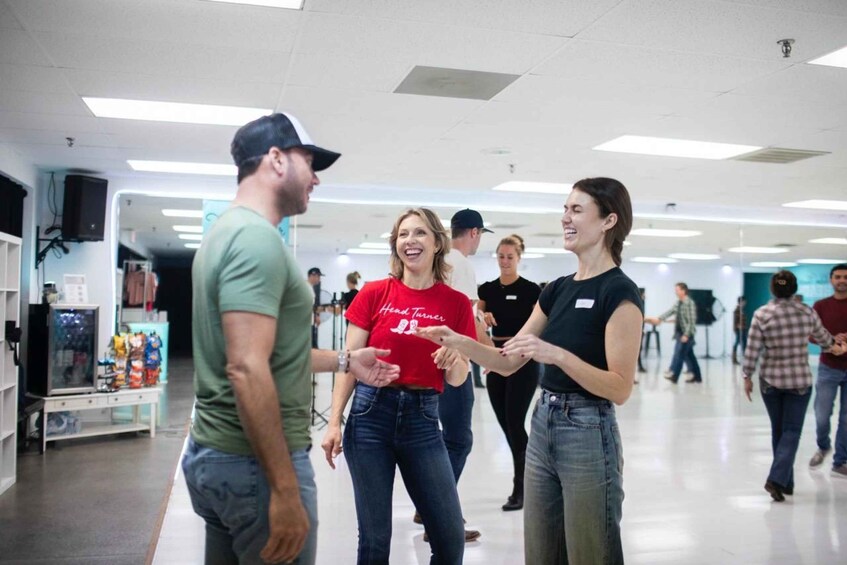 A group of people in a brightly lit indoor space with white walls and a tiled floor. 2