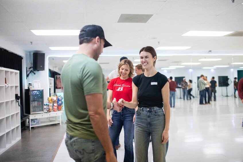 A group of people in a brightly lit indoor space with shelves and a counter in the background. 5