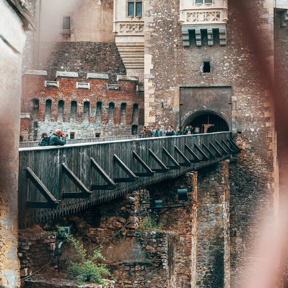 A wooden bridge over a stone wall with people walking on it. 4