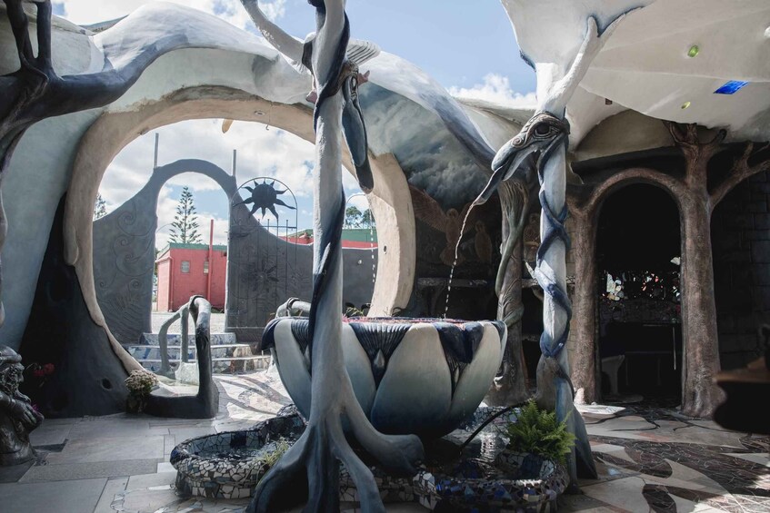 A surreal architectural structure with organic, flowing forms and a central fountain. 1