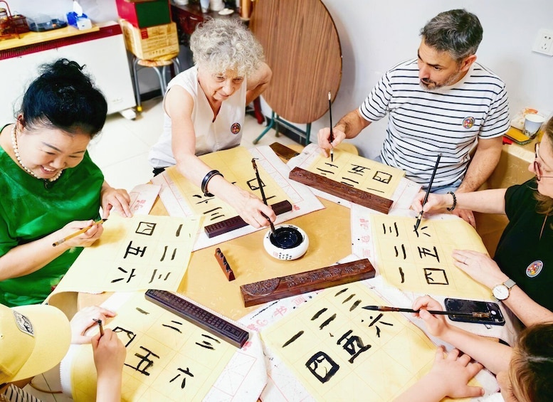 A group of people engaged in calligraphy, using brushes and ink on paper. 2