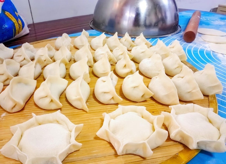 A wooden cutting board with various dumplings arranged on it. 3