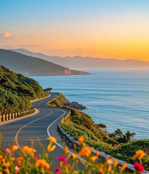 A winding coastal road with a view of the ocean and distant mountains. 1