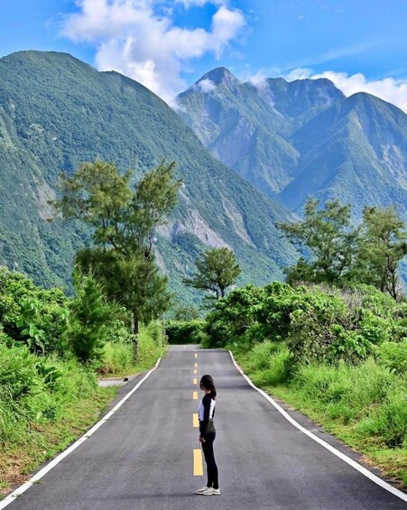 A person standing on a road with mountains in the background. 5