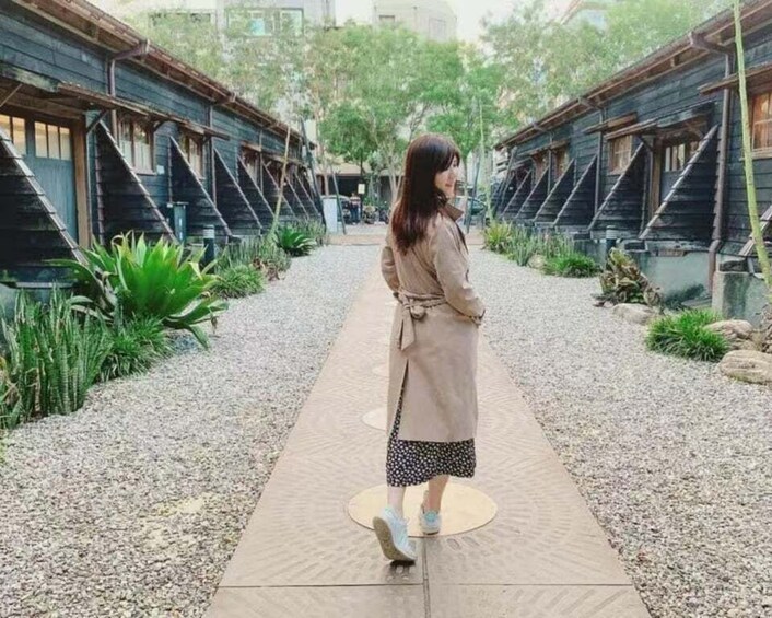 A person walking on a gravel path between wooden buildings. 4