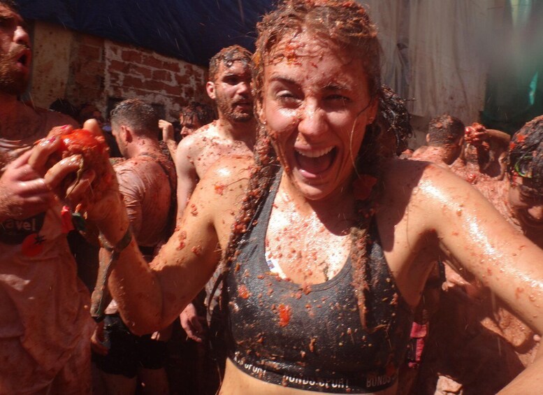 People covered in a red substance, likely participating in a mud run or similar event. 1