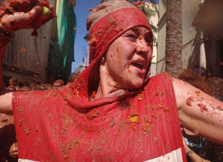 A person covered in red powder, likely participating in a cultural event. 3