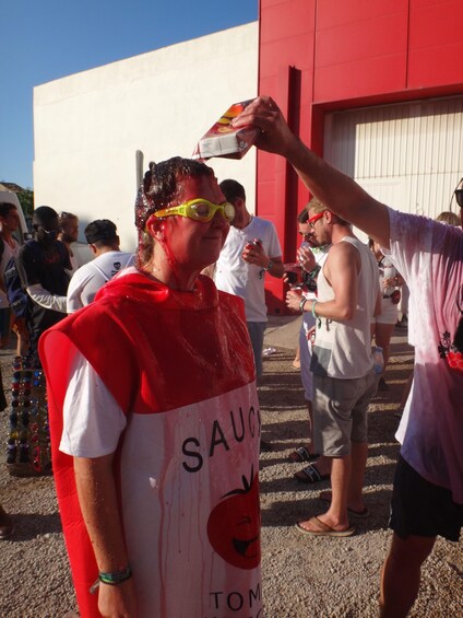 A person wearing a red and white shirt with the word "SAUG" and a tomato graphic. 4