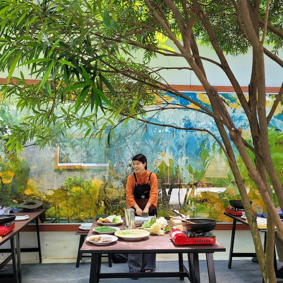 A chef preparing food outdoors with a mural in the background. 1