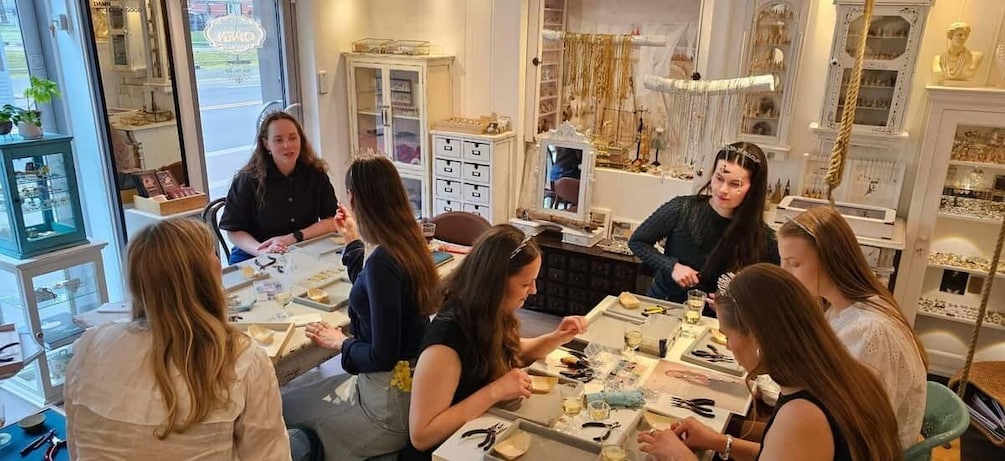 A group of people seated around a table in a jewelry store with various items on display. 2