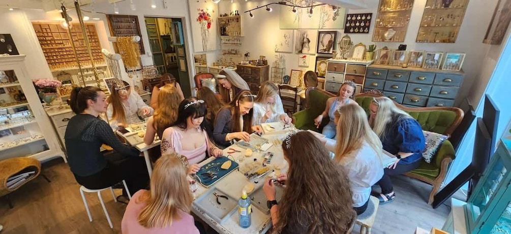 A group of people engaged in a craft activity in a well-lit room with shelves of decorative items. 1