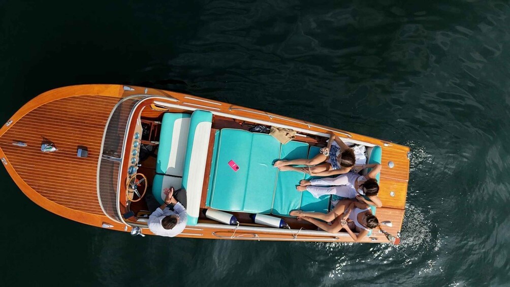 A wooden boat with a turquoise deck and a person lying on the sun loungers. 1