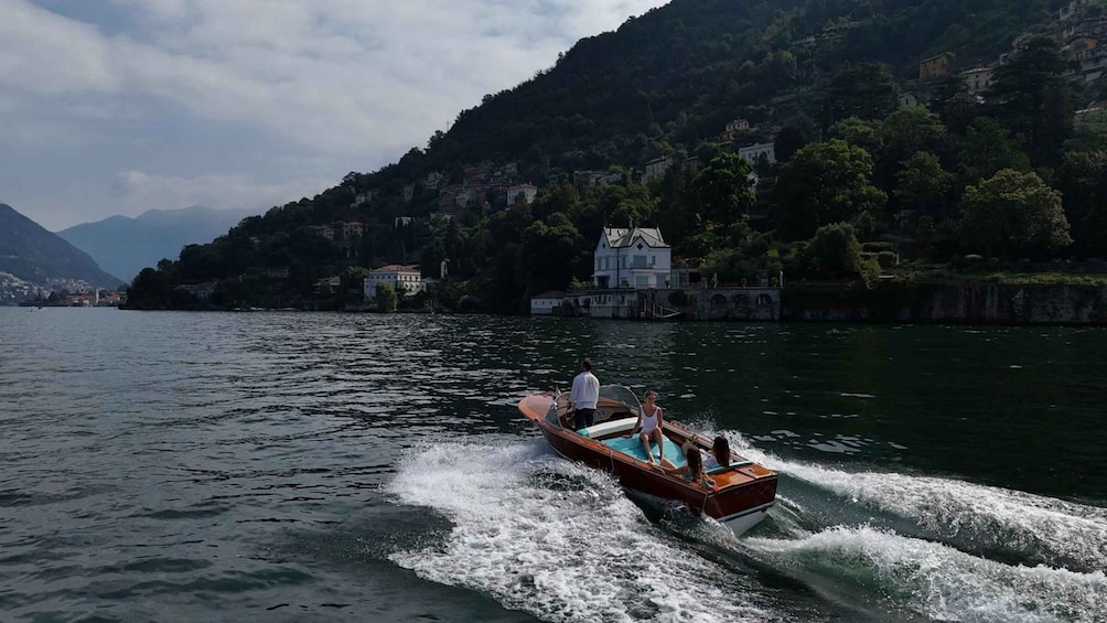 A boat speeding across a lake with houses and mountains in the background. 4