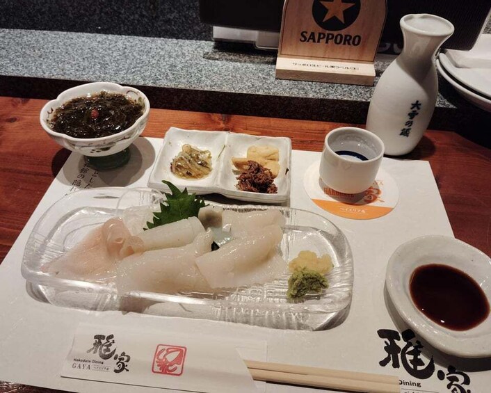 A meal with sashimi, miso soup, and soy sauce on a wooden table. 1