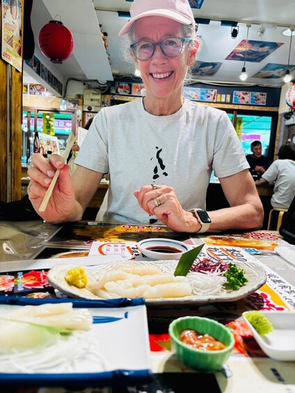 A person seated at a table with various dishes, chopsticks, and a bowl of sauce. 3
