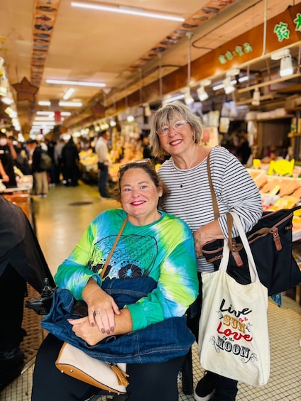An indoor market with people shopping and vendors selling goods. 2