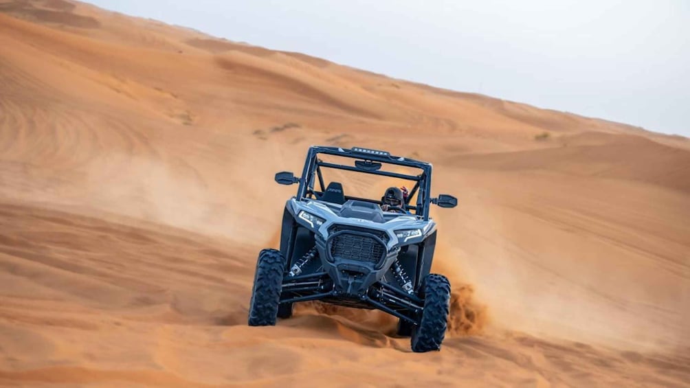 A Polaris RZR navigating a sandy dune. 1