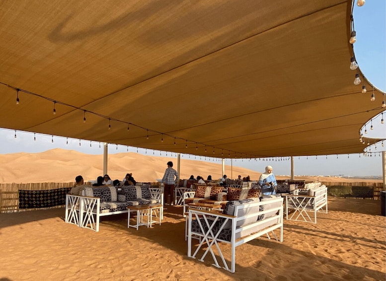A desert tent with people sitting and standing under a canopy. 3