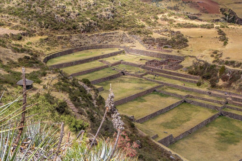 An ancient terraced structure with stone walls and grassy terraces, surrounded by dry grassland and sparse vegetation. 5
